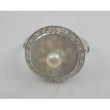 A LADY'S DRESS RING having central pearl on a circular mother-of-pearl disc bordered by small