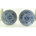 A PAIR OF ORIENTAL BLUE AND WHITE DRAGON DECORATED LOTUS RIMMED SHALLOW BOWLS each 31cm diameter