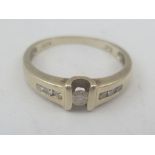 A DIAMOND RING with central stone and three stone set shoulders, indistinctly marked, possibly 18ct