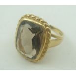 A 9CT GOLD RING set with a large smoky quartz in a rope design border, stamped .375