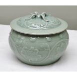 A CHINESE CELADON GROUND LIDDED POT, relief moulded with flower heads and stud work, having a four-