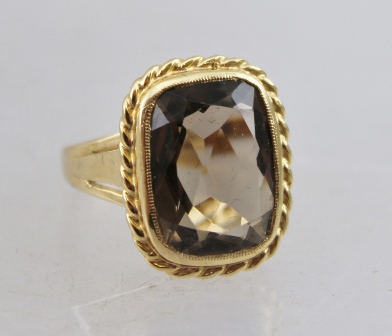 A LADY'S 9CT GOLD DRESS RING, set with large smoky quartz within a rope twist border, ring size M