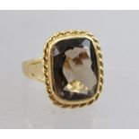 A LADY'S 9CT GOLD DRESS RING, set with large smoky quartz within a rope twist border, ring size M