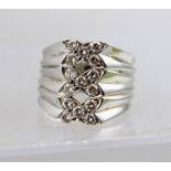 A HEAVY LADY'S DRESS RING set with fifteen diamonds arranged in three bow setting, unmarked,