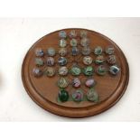 THIRTY-TWO HAND-MADE GLASS MARBLES together with a mahogany SOLITAIRE BOARD