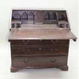 A GEORGE III OAK BUREAU, the fall front revealing a fitted interior of pigeon holes and drawers