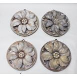 A SET OF FOUR RECONSTITUTED MARBLE EFFECT WALL PLAQUES of flower head design, 36cm diameter