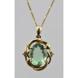 A 9CT GOLD GREEN STONE SET PENDANT in a scrolling frame set with two small stones, on chain