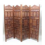 A 20TH CENTURY PROBABLY INDIAN CARVED HARDWOOD FOUR-PANELLED FOLDING SCREEN, comprising pierced