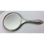 A HAND HELD SILVER VANITY MIRROR, the back engraved with ribbon swags supporting a basket of