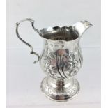 A GEORGE III SILVER CREAM JUG of baluster form, the body decorated with repousse flowers and a blind