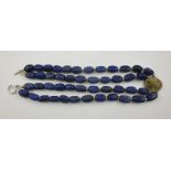 A LAPIS LAZULI BEAD NECKLACE, set with a lava cameo carved with a classical portrait in profile