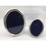 TWO PLAIN OVAL SILVER PHOTOGRAPH FRAMES with blue velvet easel backs, largest would take an image