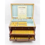 A MAHOGANY CASED MAH JONG SET, INLAID BOX with hinged cover, over drawers, raised on ogee bracket