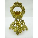 A BRASS WATCH HOLDER having putti and wreath decoration, 16cm high