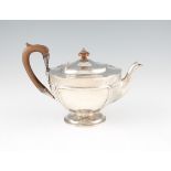 A silver tea pot, of circular form and raised on single stepped circular foot, with wooden handle