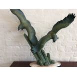 A large hollow bronze Art Deco style figure group of two sea eagles on a two tone marble base.