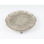 A silver salver, with pie crust rim and raised on four scroll feet, hallmarked with Birmingham bi-