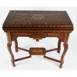 A Moroccan fold over games table with extensively inlaid body and interior, the hinged lid revealing