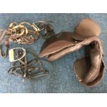 A brown leather horse saddle with stirrups and straps.