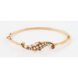 A rose metal pearl hinged bangle bracelet, the open metal work scroll design set with graduated