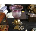 A brass table lamp with pink glass frosted shade.