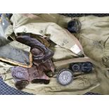 A size 5 WWII flight suit together with two flight caps, a compass, and several gauges.