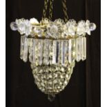 A brass chandelier with glass droppers and glass flowers to top.