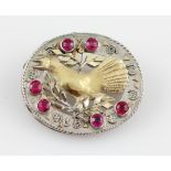 An oval bird design brooch, the open metalwork design set with six round cut rubies (possibly