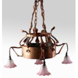 An arts and craft hand beaten copper ceiling light fitting, with four pink glass shades