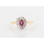 A ruby and diamond cluster ring, set with a central oval cut ruby, measuring approx. 4x3mm,