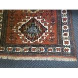 A Persian style terra cotta coloured rug with three medallions to centre and a cream and blue border