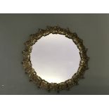 A round silver on brass wall mirror decorated with grapes and vines.