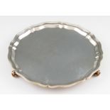 A silver salver with pie crust rim, raised on three scroll feet, hallmarked Chester 1941, makers