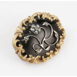 A memorial pin brooch set with seed pearls, featuring floral design and scroll edge border,