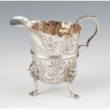 An early 20th Century Irish silver jug, of repousse animal, floral and foliage design with pie crust