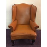 A mahogany wingback fireside armchair with claw and ball feet.