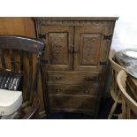 An oak three drawer, two door cabinet with carved floral design.