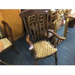 A stained wood lath back kitchen armchair.