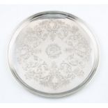 An early 20th Century silver salver, the circular form engraved with scrolling floral and foliage