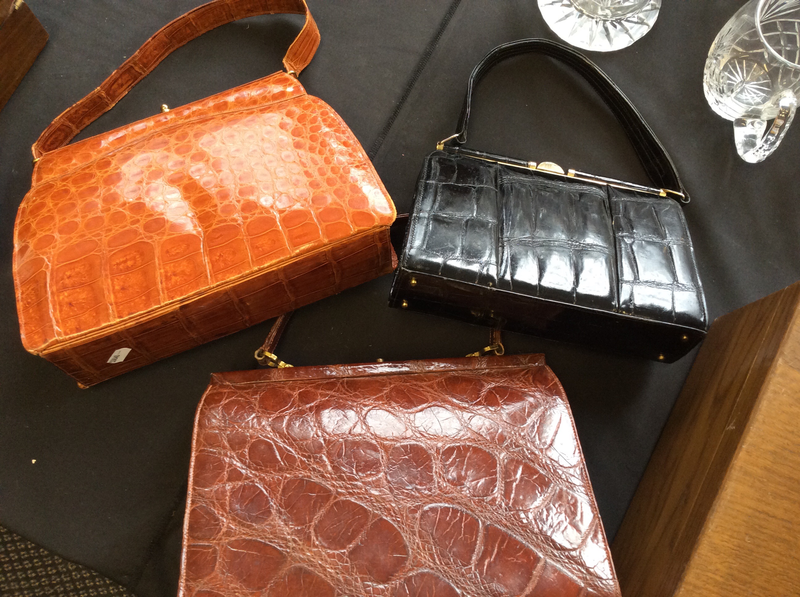 Three leather handbags, two brown, one black.