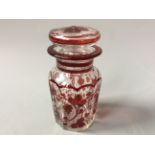 A bohemian glass lidded decanter with red vine detail with an iridescent shell shaped glass vase.