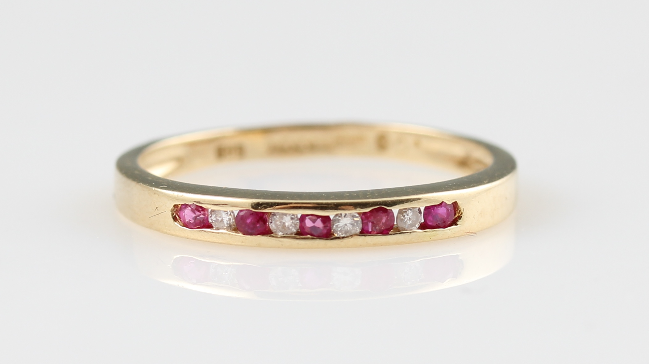 A 14ct yellow gold ruby and diamond half eternity ring, channel set with alternating round cut