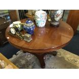 A reproduction mahogany circular extending table with spare leaf on centre pedestal.