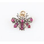 A ruby and diamond set dragonfly pendant, set in unmarked white metal.