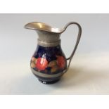 A Moorcroft hand beaten pewter water jug in Pomegranate design for Liberty, signed William Moorcroft