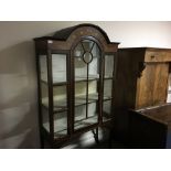 A glazed panel front mahogany cabinet with floral inlay design.