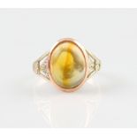 A fire opal ring, set with an oval fire opal cabochon, in an open metalwork setting, set in unmarked