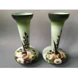 A pair of Victorian green glass vases with hand painted floral and bird design.