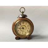 A walnut cased alarm clock on wheel feet. Height 24cm.